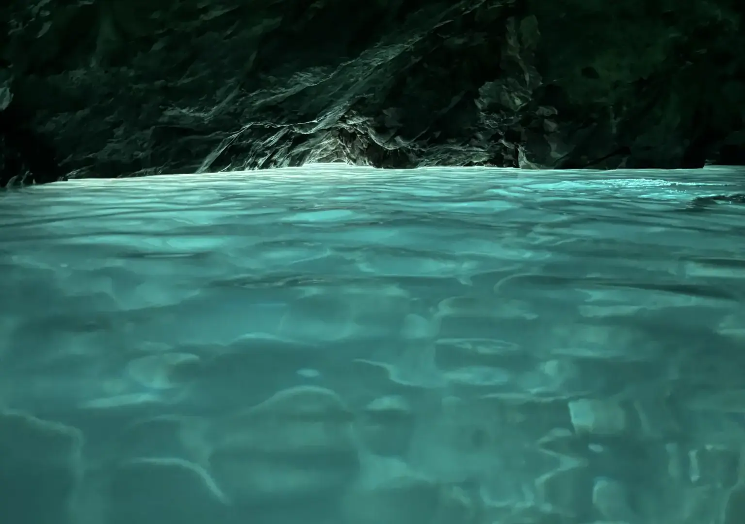 Rippled green-blue water at water level inside the Blue Cave, with a dark rock wall and a pale band of light along the waterline
